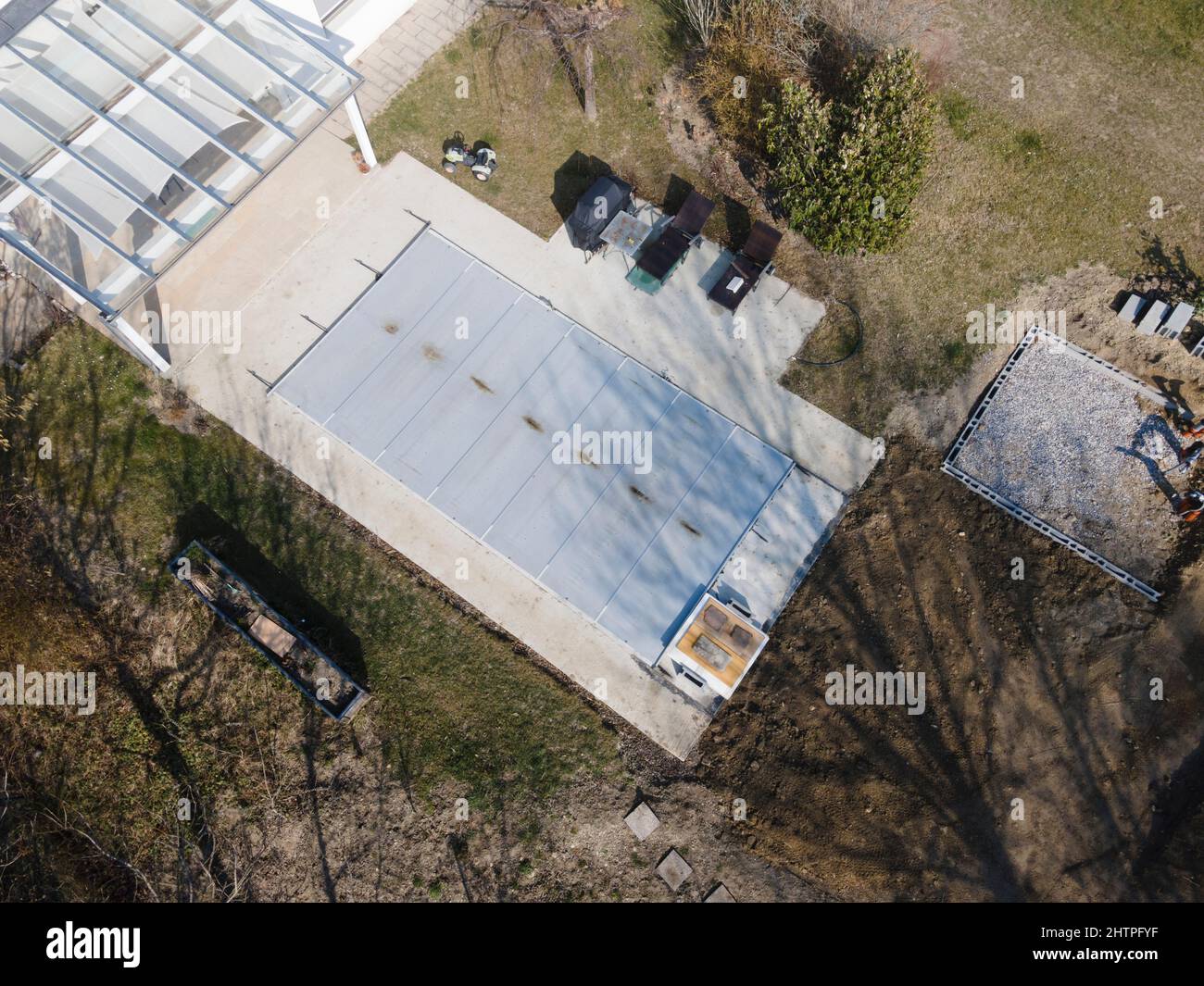 Un drone survolait une piscine couverte avec une bâche encore en construction dans un jardin Banque D'Images