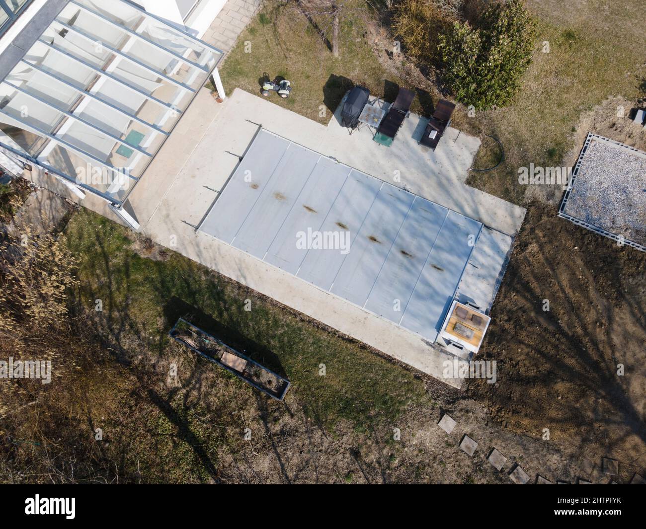 Un drone survolait une piscine couverte avec une bâche encore en construction dans un jardin Banque D'Images