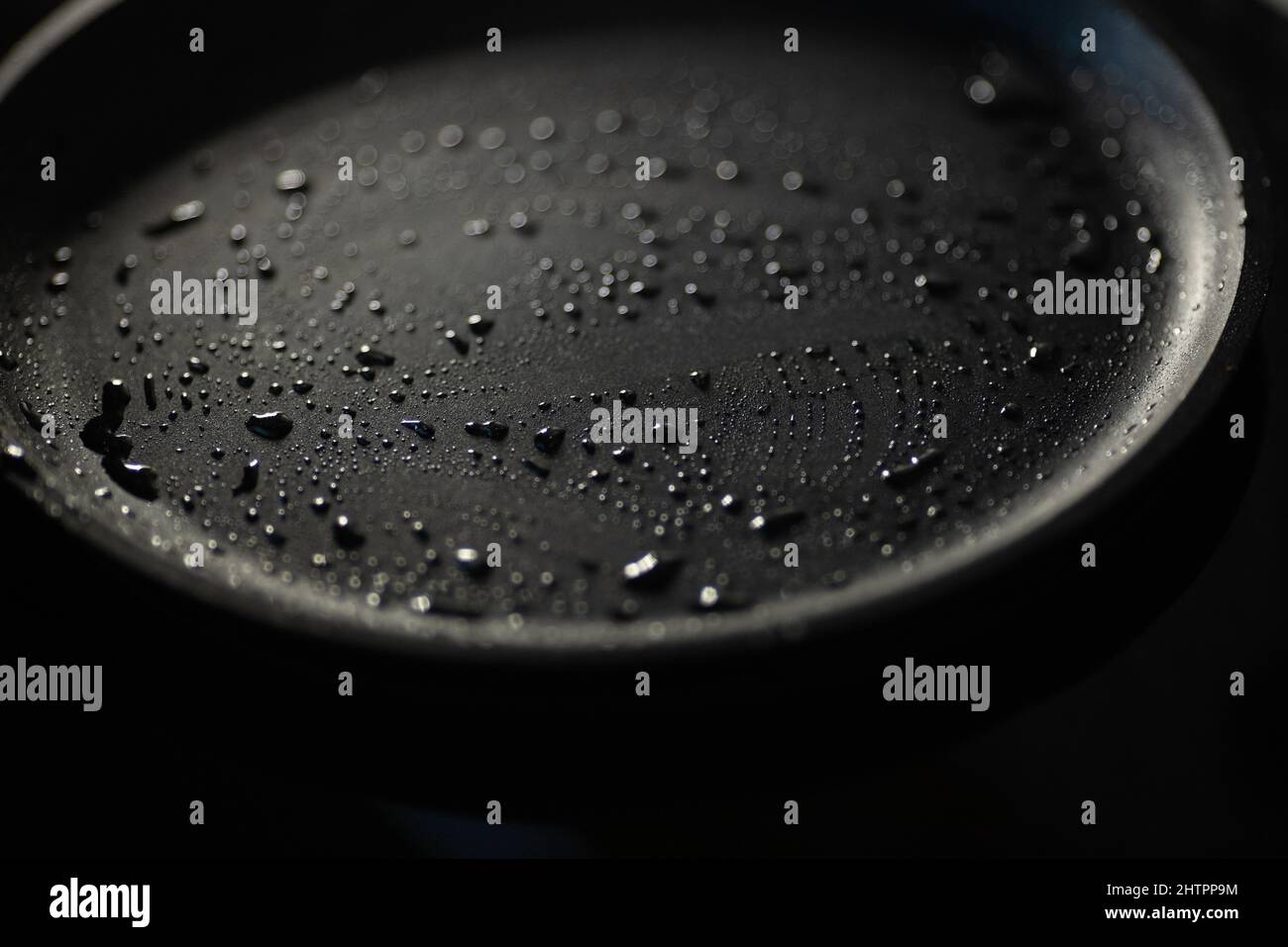 Fait partie d'une casserole vide en fonte de couleur noire avec des gouttes d'huile végétale. Gros plan. Arrière-plan sombre. Commencez la cuisson Banque D'Images