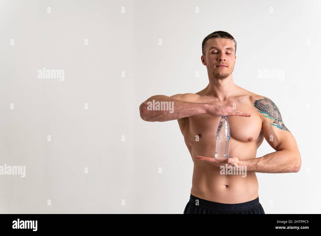 La forme physique à l'eau potable est pompée avec une serviette sur un fond blanc corps ajusté isolé, sport aquatique homme adulte, cardio de fond. Protéine de force Banque D'Images