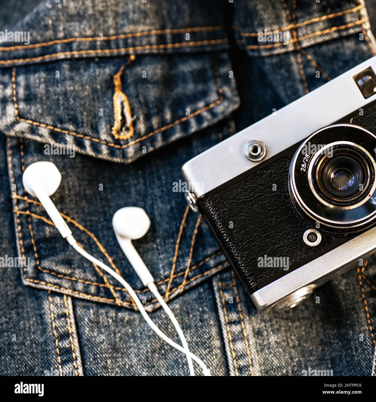 L'appareil photo et le casque avec fil blanc reposent sur l'arrière-plan du denim. Arrière-plan tendance des vêtements taille basse. Style rétro. Journée des photographes. Vue de dessus Banque D'Images