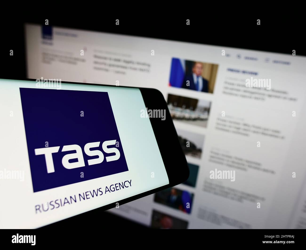 Téléphone portable avec logo de l'agence de presse russe TASS (TACC) à l'écran en face du site Web des entreprises. Effectuez la mise au point au centre-droit de l'écran du téléphone. Banque D'Images