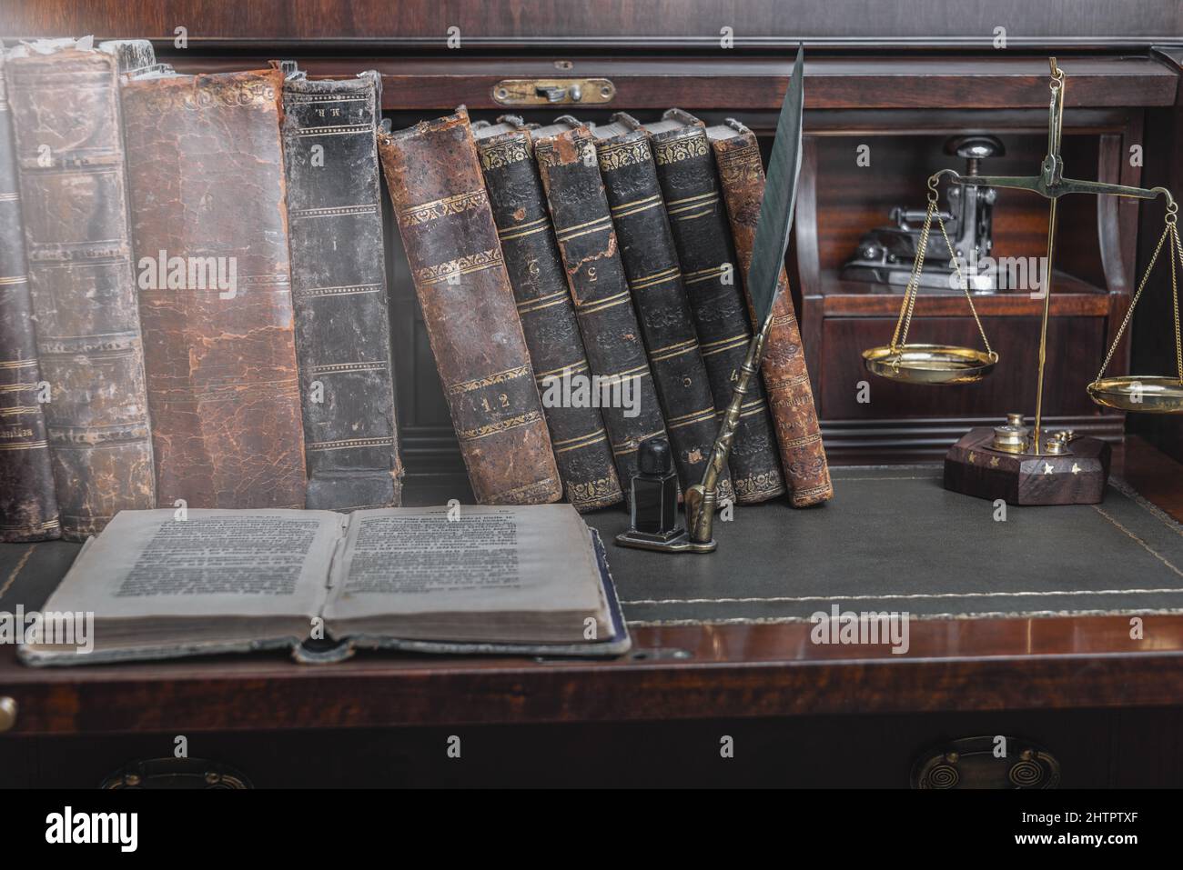 Plume d'anciens, livres et encrier vintage sur un bureau en bois dans l'ancien bureau dans le contexte de la bibliothèque et les rayons de lumière. Conceptual Banque D'Images
