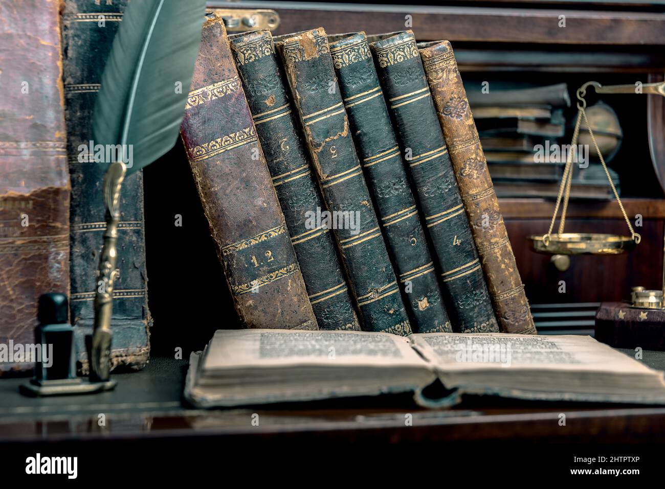 Plume d'anciens, livres et encrier vintage sur un bureau en bois dans l'ancien bureau dans le contexte de la bibliothèque et les rayons de lumière. Conceptual Banque D'Images
