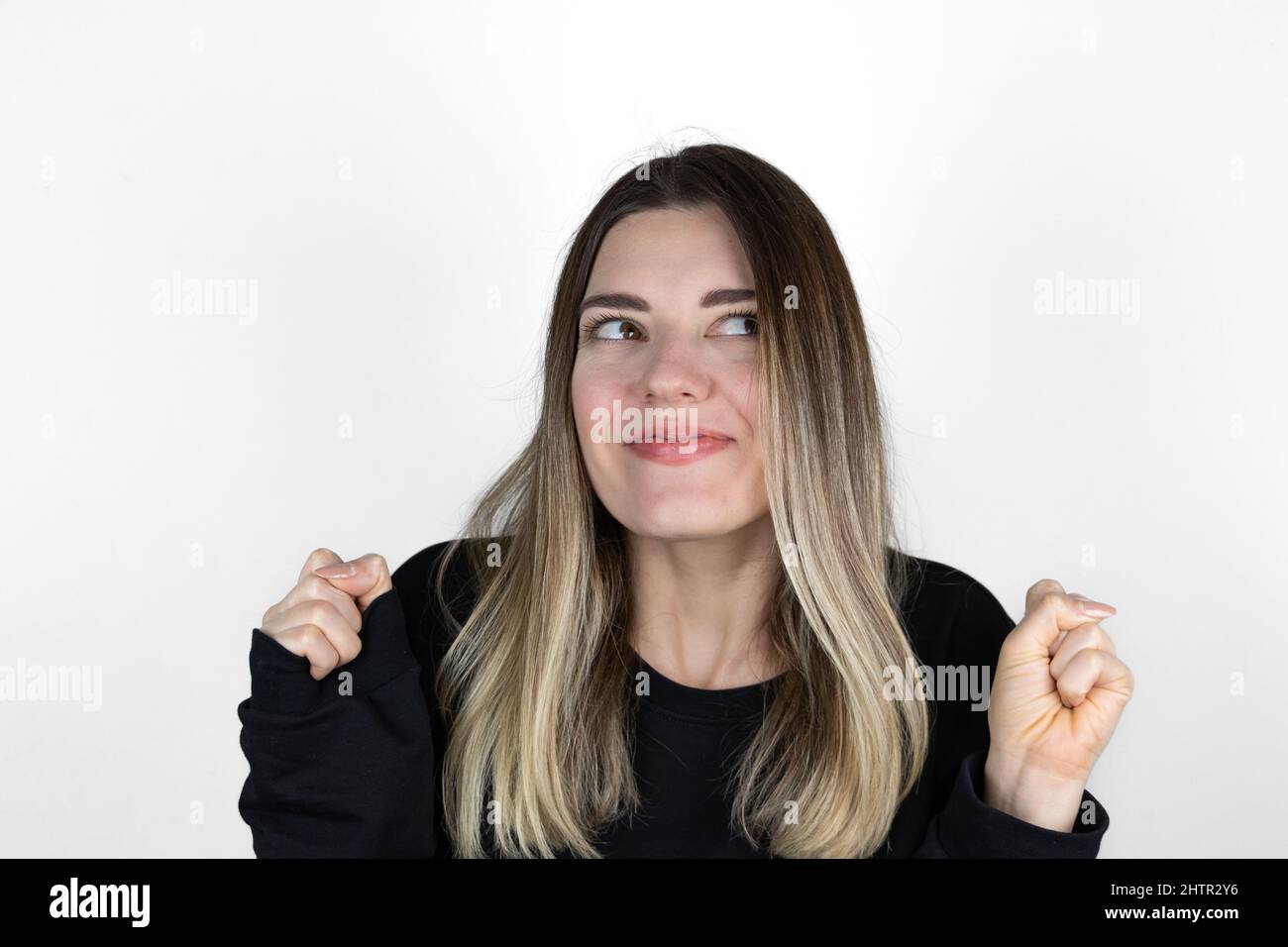 La fille a les deux mains à son côté. Trop heureux sur fond blanc. Crier. Elle a eu de bonnes nouvelles. Quelque chose qu'elle voulait est arrivé vrai. Gagnant. Banque D'Images