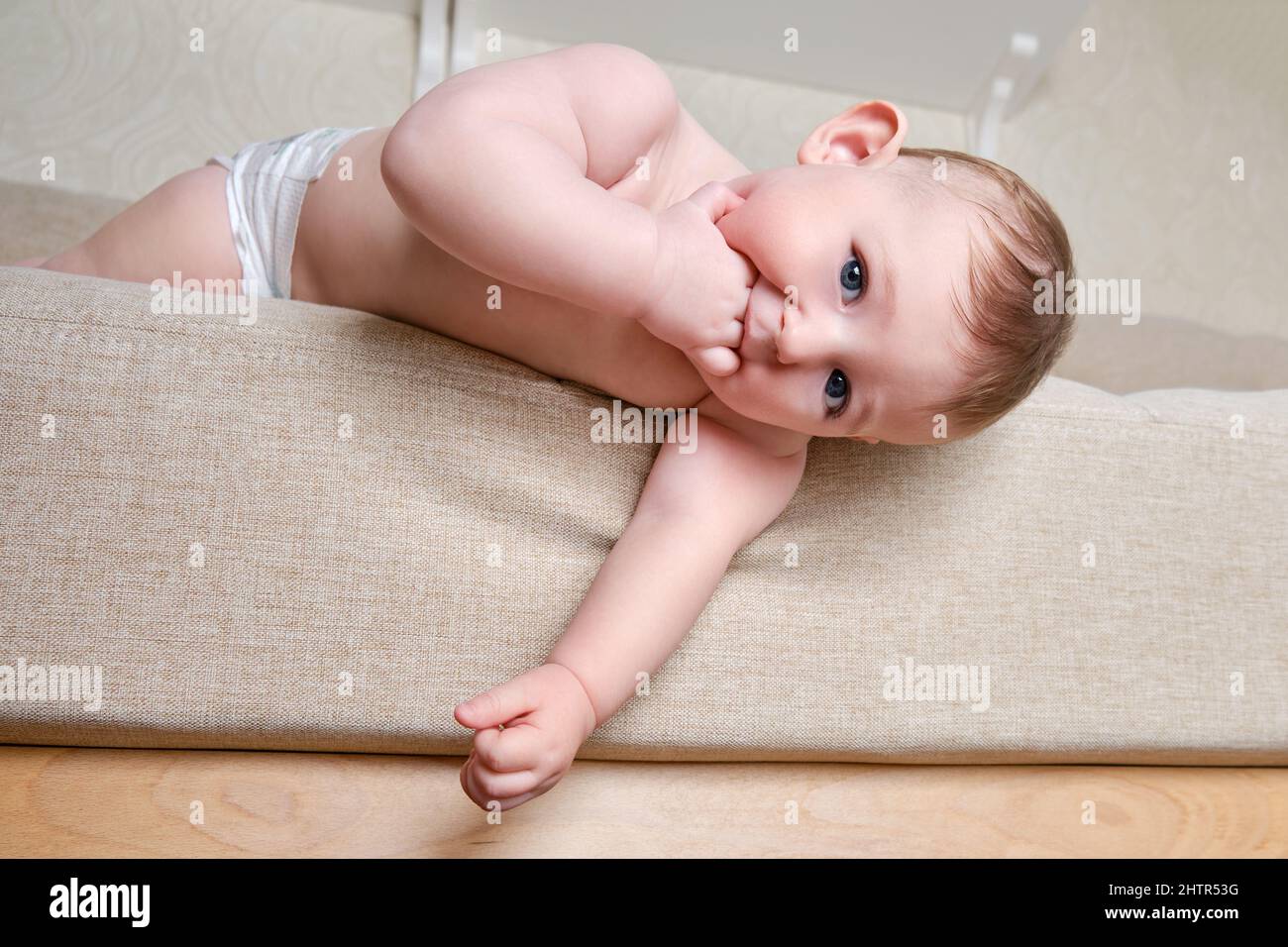 Bébé tombe du canapé dans le salon de la maison. Le tout-petit sort du lit.  Problèmes avec la sécurité des enfants sans surveillance parentale Photo  Stock - Alamy