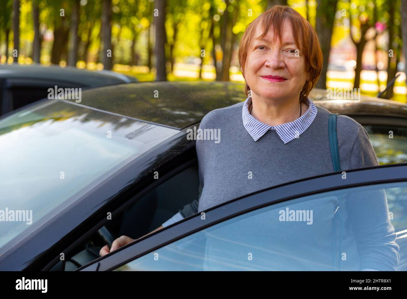 Femme mature positive debout à côté de sa voiture Banque D'Images
