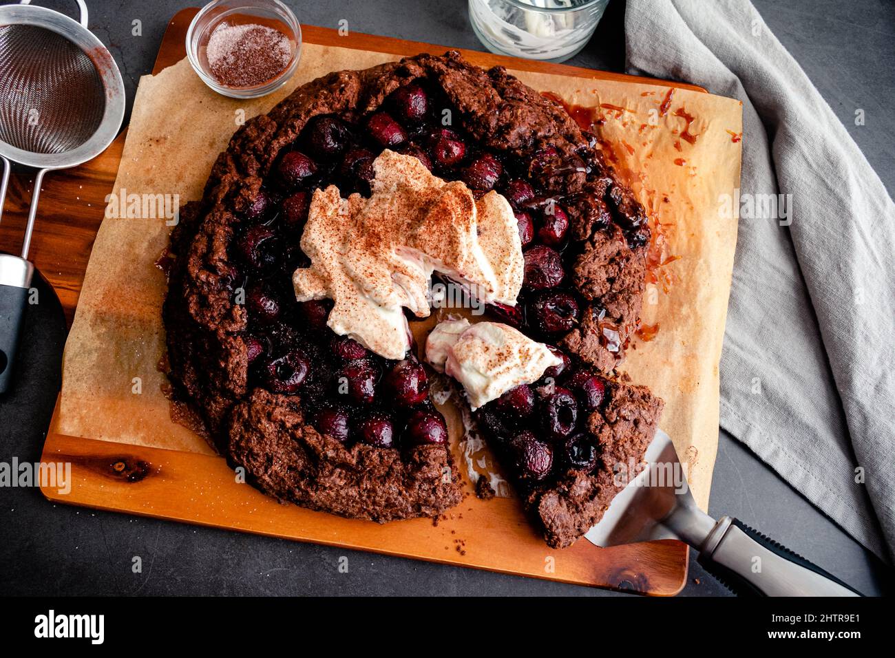 Galette de chocolat de cerise Bourbon en tranches recouverte de crème fouettée : galette de cerise noire rustique recouverte de crème fouettée Banque D'Images