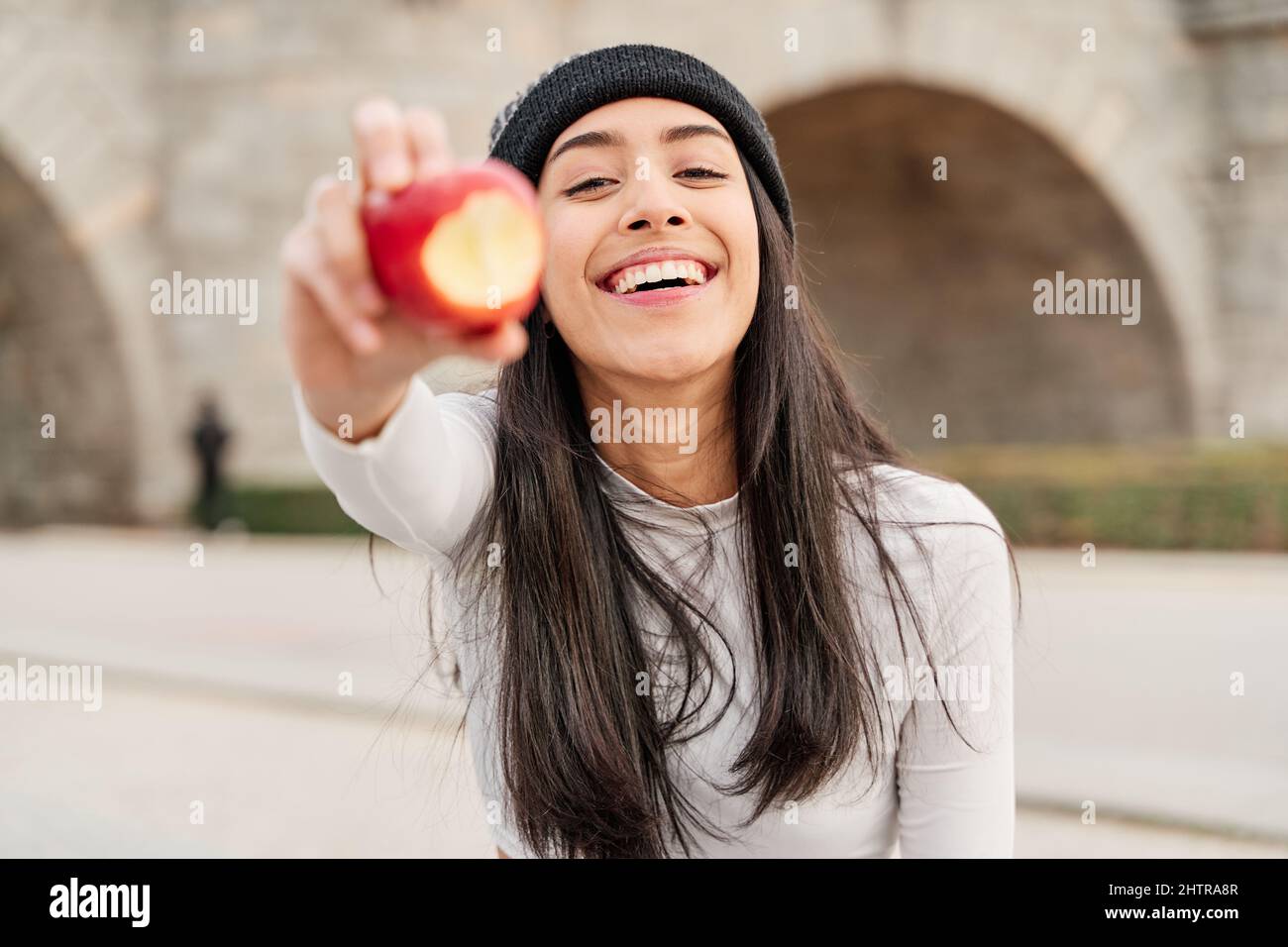 Jeune et belle femme latine tenant une pomme mordue et la montrant à la caméra. Femme avec des dents parfaites manger sainement, concept de vie saine Banque D'Images