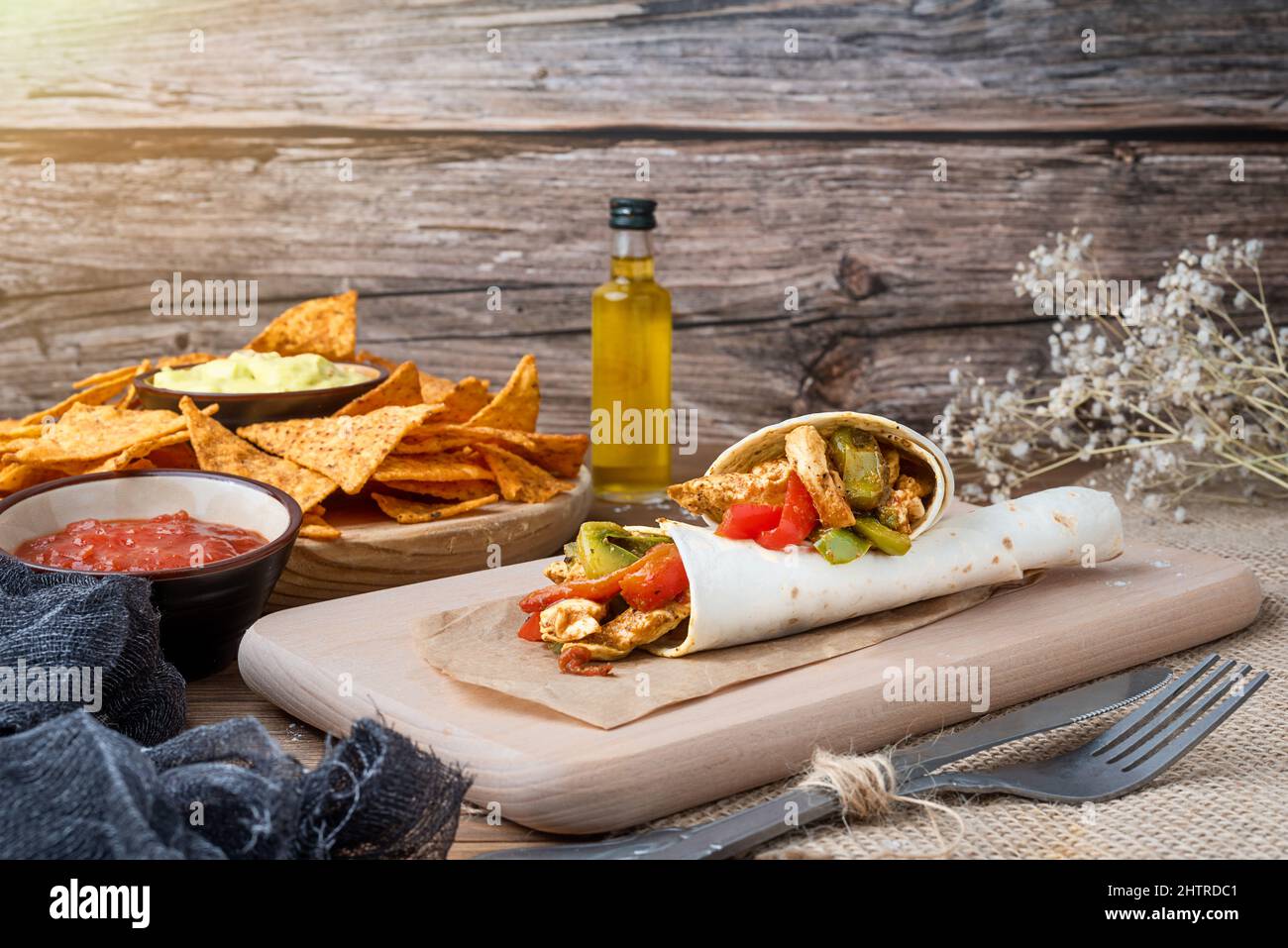 Fajitas au poulet avec poivrons, oignons et épices et sauce guacamole avec chips de tortilla ou nachos sur une table en bois Banque D'Images