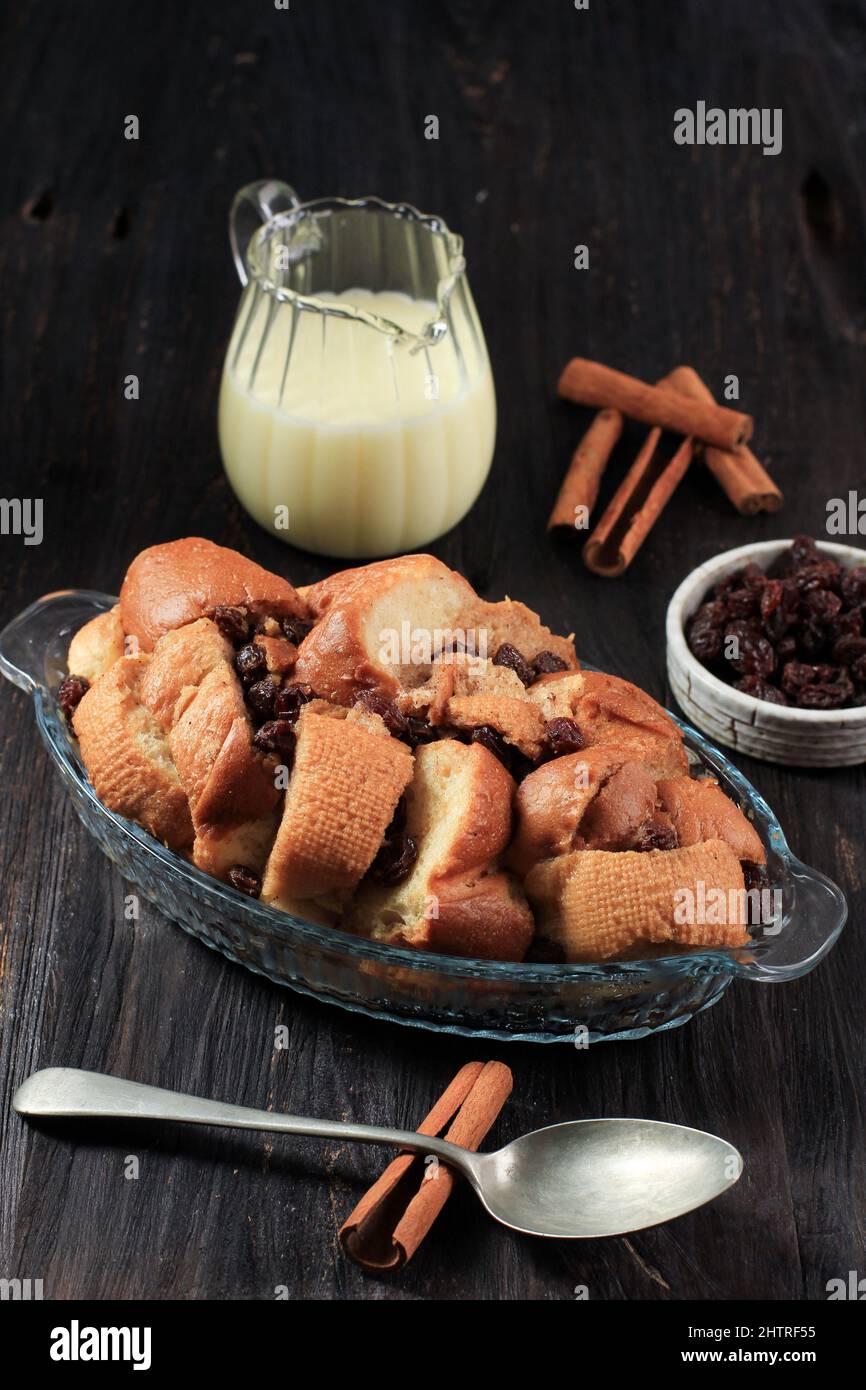 Pain à la cannelle et au beurre Pudding aux raisins secs dans un plat de cuisson transparent, servi avec du VLA. Sur une table en bois Banque D'Images