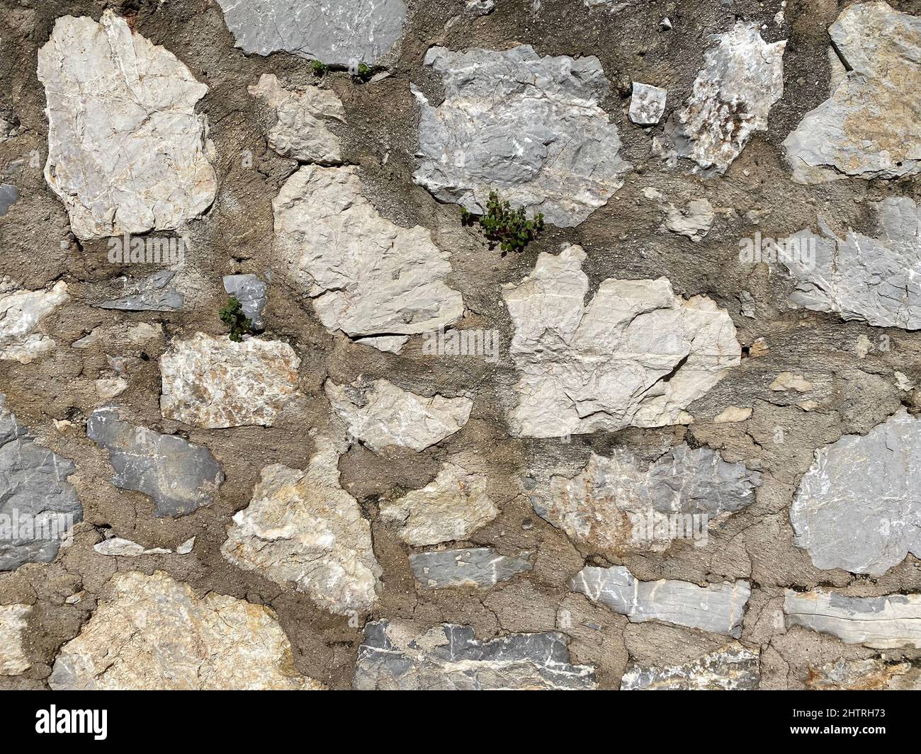 Mur en pierre. Un vieux mur de pierre a été construit avec plus de ciment. Gros plan. Banque D'Images