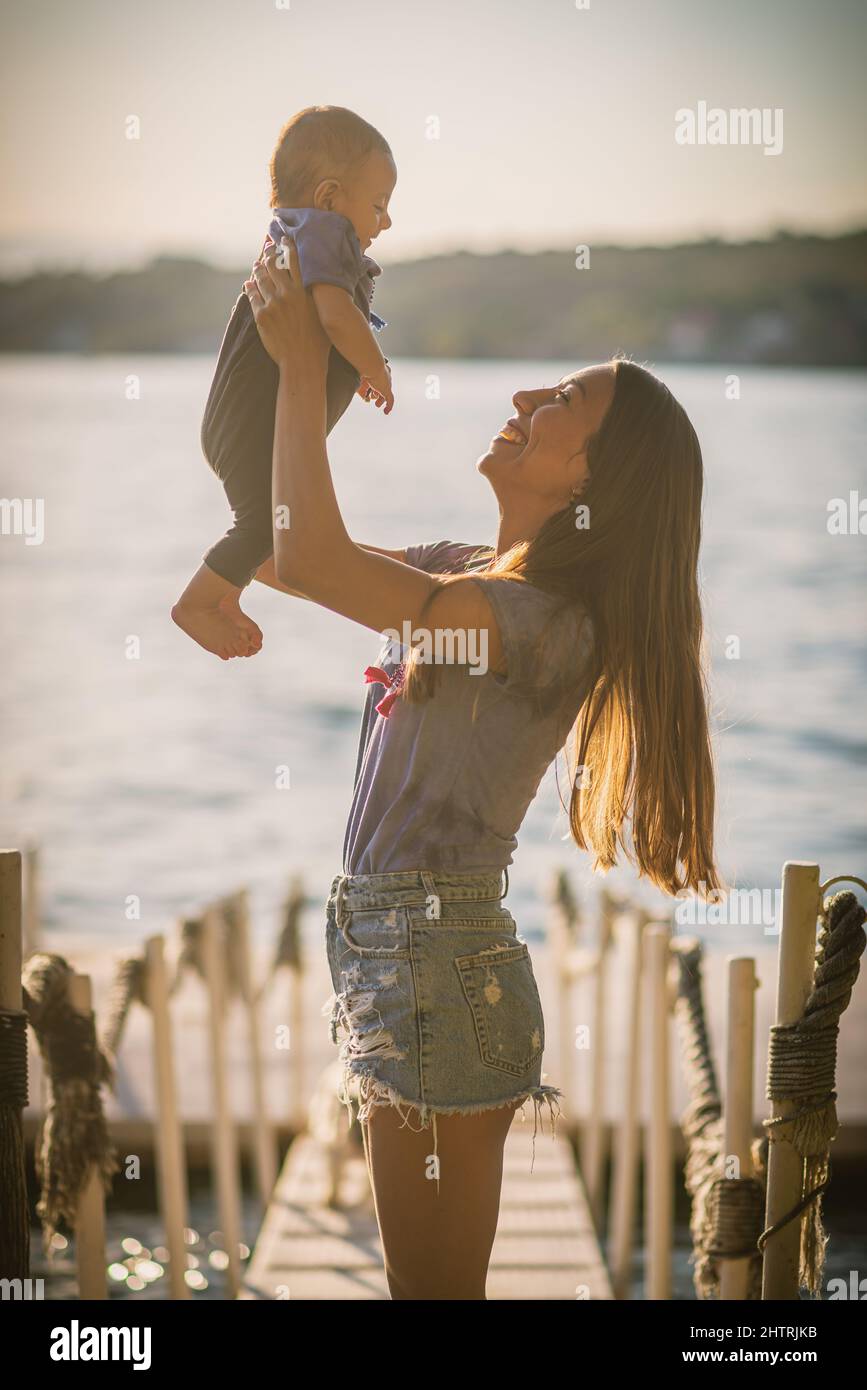 Maman avec son bébé garçon jouant au bord du lac un après-midi ensoleillé Banque D'Images