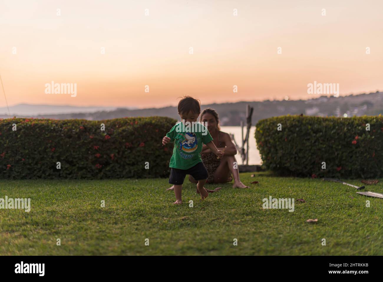 Un petit garçon apprend à marcher sur l'herbe un soir d'été Banque D'Images