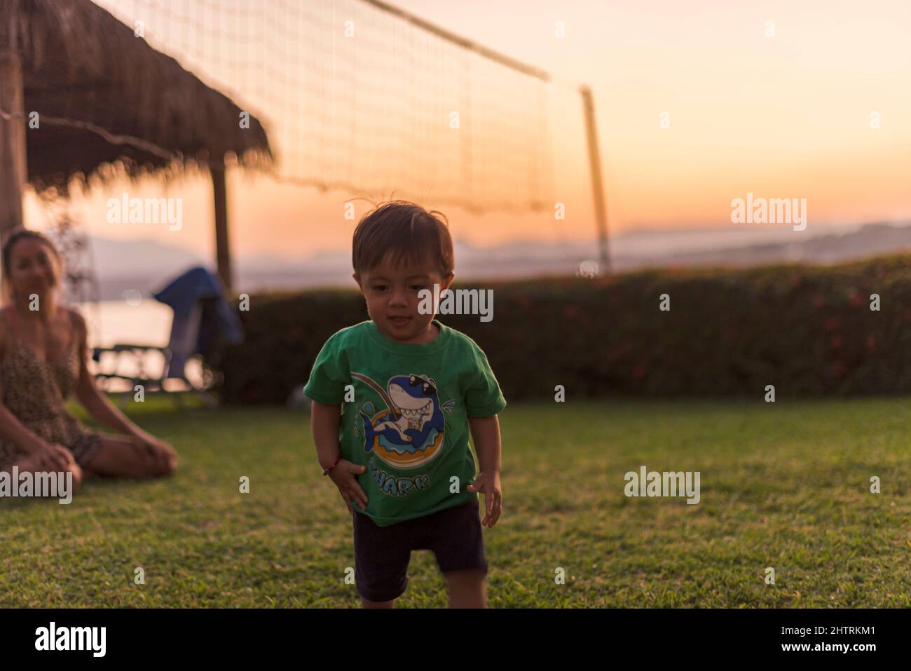 Un bébé heureux qui marche sur l'herbe lors d'une chaude soirée d'été Banque D'Images