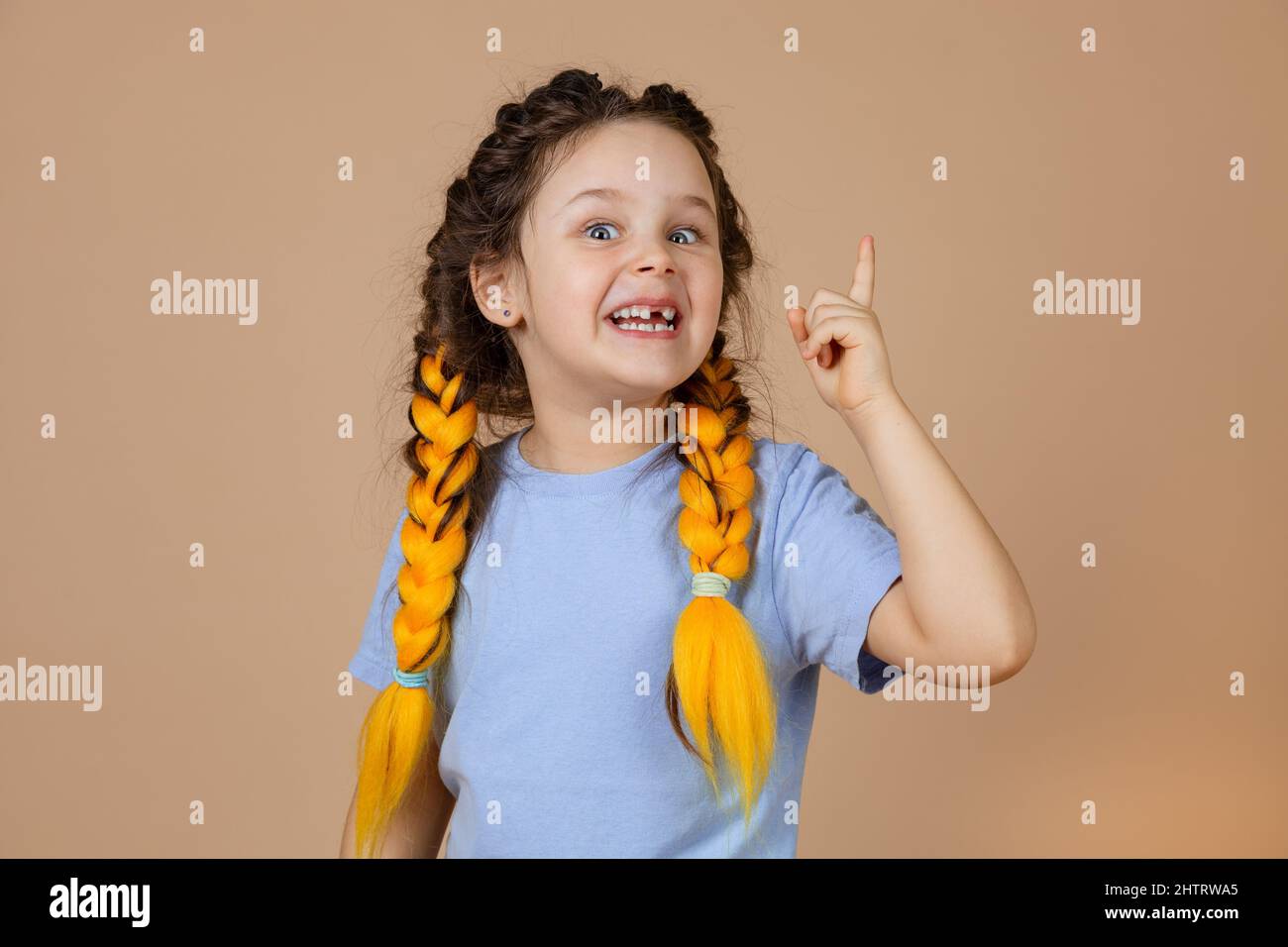 Sly insidieux fille intelligente ayant jaune kanekalon braides montrant le pointeur ayant eureka moment ayant une grande idée dans la tête sur fond beige Banque D'Images
