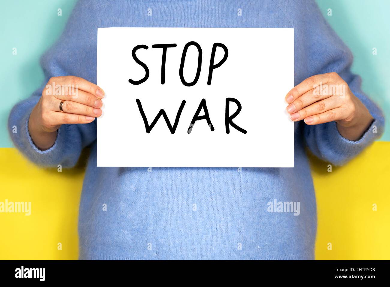 Une femme porte un foulard avec l'inscription Stop the war sur fond de drapeau ukrainien. Arrêter la guerre. Banque D'Images