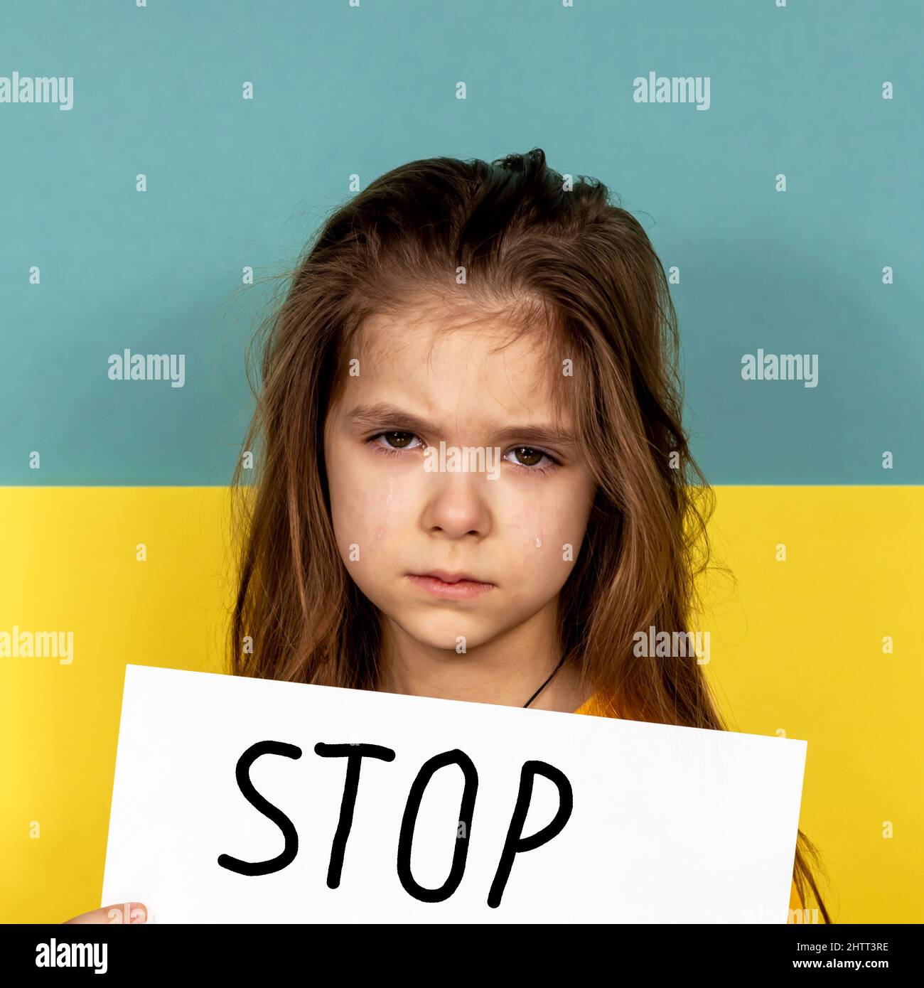Le visage d'une fille qui pleure en gros plan. Une fille tient une AFFICHE D'ARRÊT dans ses mains contre le fond du drapeau ukrainien. Arrêter la guerre en Ukraine. Le Banque D'Images