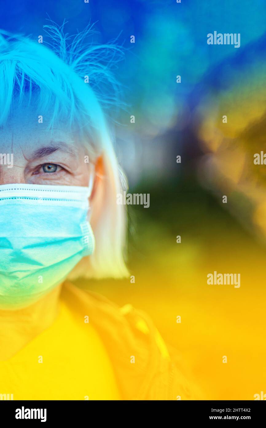 Drapeau national de l'Ukraine dans les couleurs bleu jaune et visage de femme dans le masque de protection respiratoire médical Banque D'Images