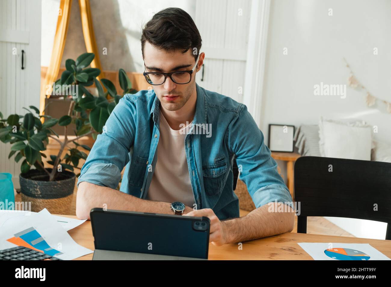 Un jeune homme gère ses finances depuis son domicile. Économiste travaille chez lui, indépendant Banque D'Images