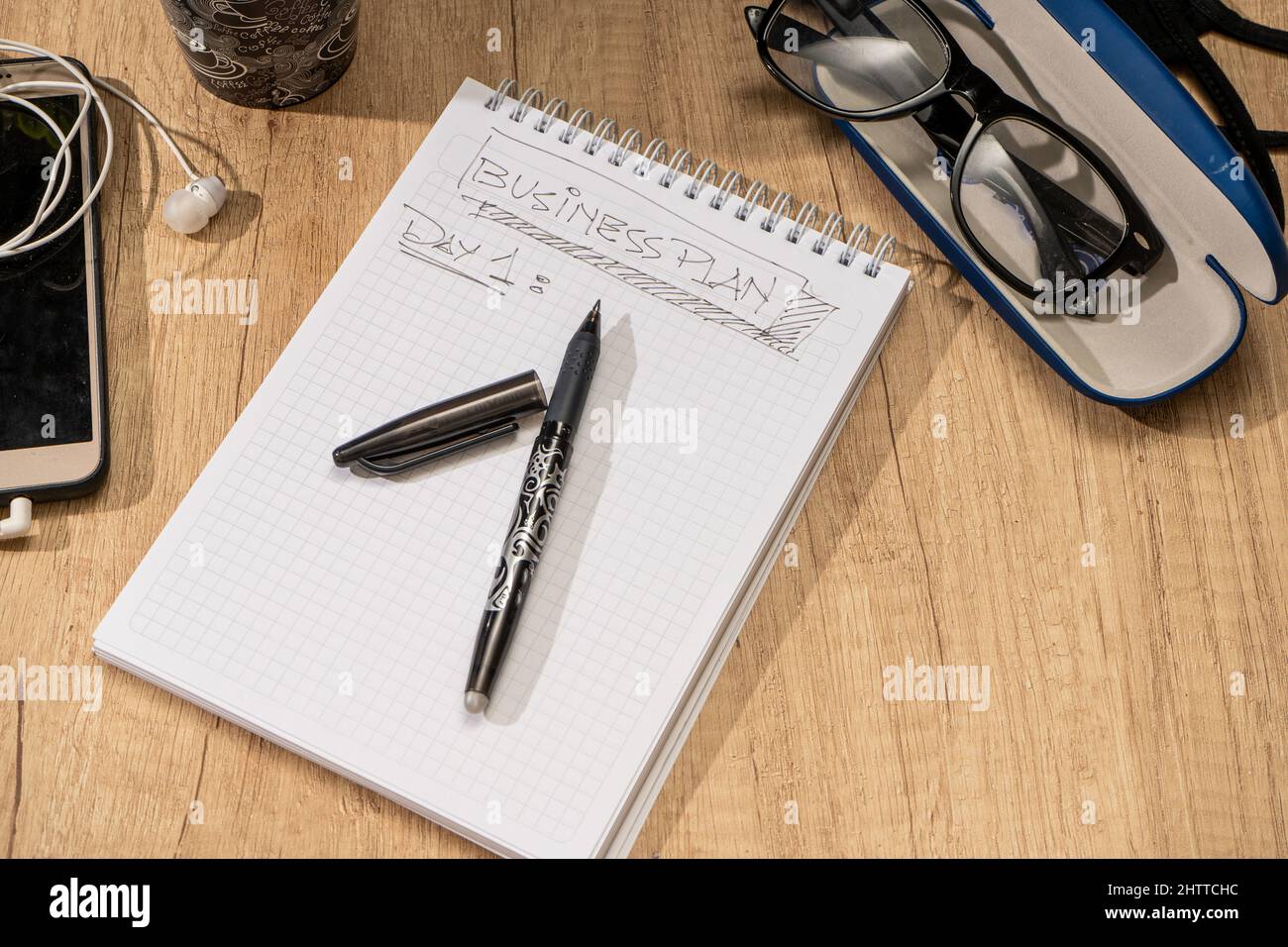 Surface d'un bureau en bois avec bloc-notes, stylo, lunettes, calculatrice et téléphone portable. Bureau de travail. Banque D'Images