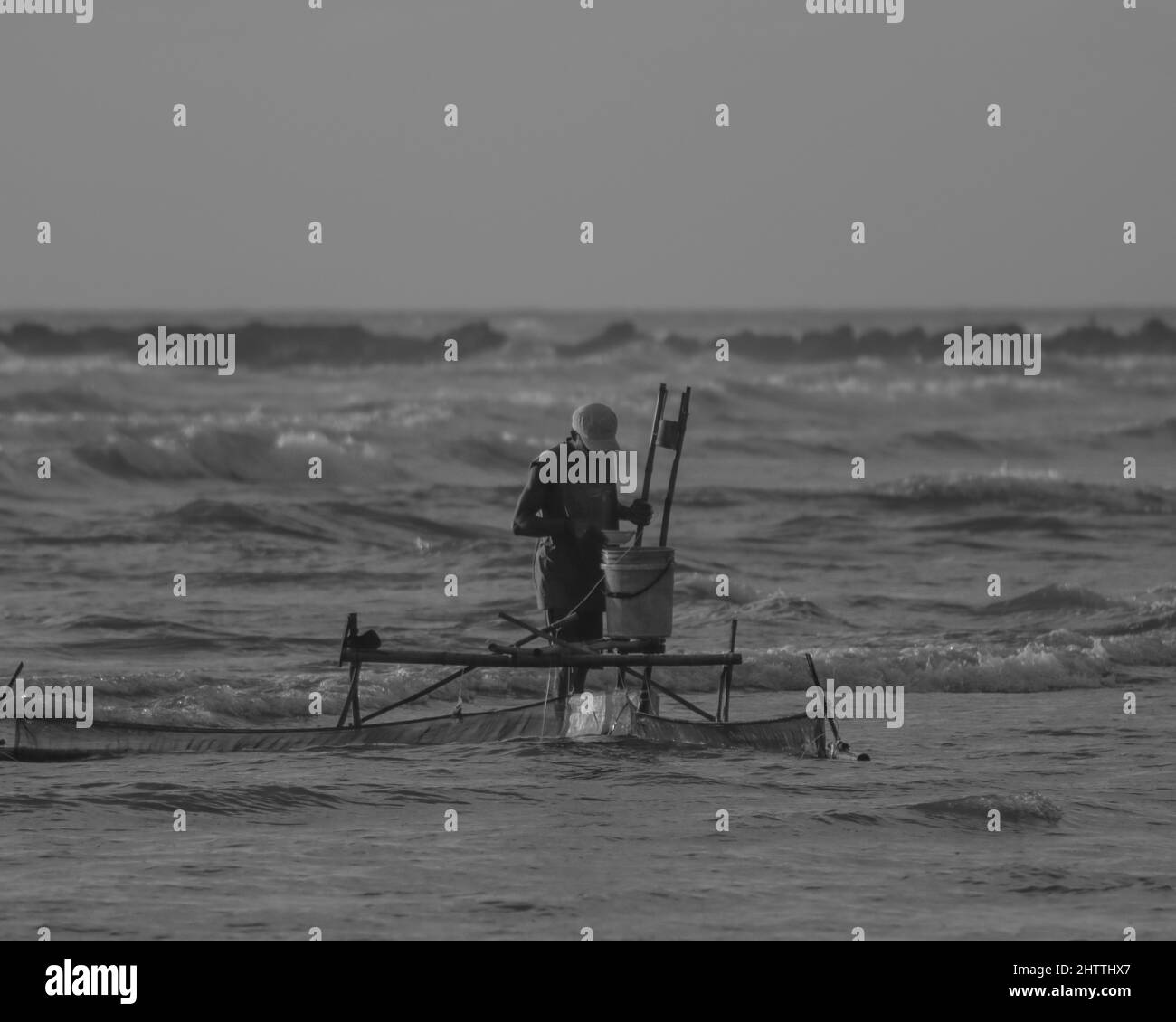 Photo noir et blanc d'un pêcheur qui attrape du poisson dans l'eau Banque D'Images