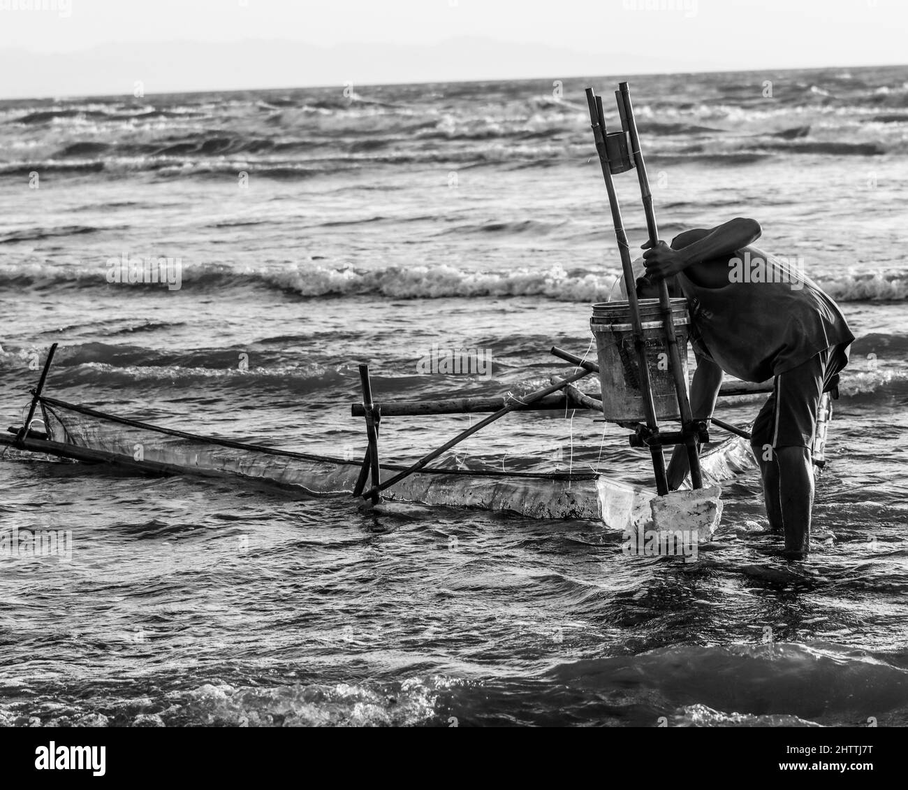 Photo noir et blanc d'un pêcheur qui tente de pêcher dans l'eau Banque D'Images