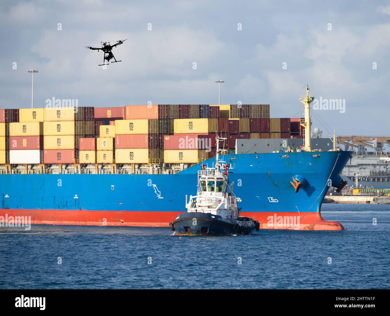 Drone volant au-dessus du navire porte-conteneurs et du remorqueur. Concept : technologie de drone, Mer Rouge, attaque, surveillance de détournement, sécurité, attaque de drone... Banque D'Images