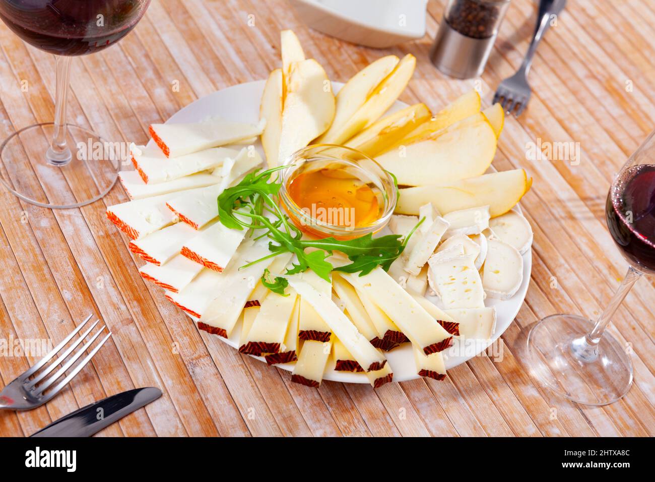 Assiette avec différents types de fromage et une tasse de miel Banque D'Images