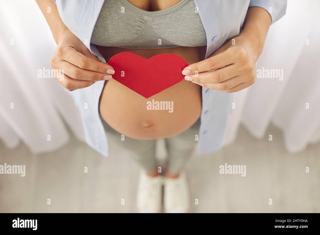 Vue de dessus de la femme enceinte tenir le coeur de papier sur le ventre Banque D'Images