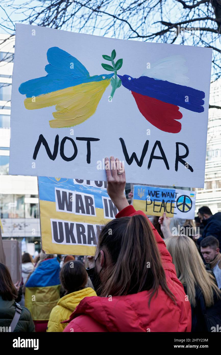 Une protestataire féminine tenant une affiche de protestation contre l'invasion russe de l'Ukraine, deux colombes de la paix dans les couleurs nationales de l'Ukraine et de la Russie Banque D'Images