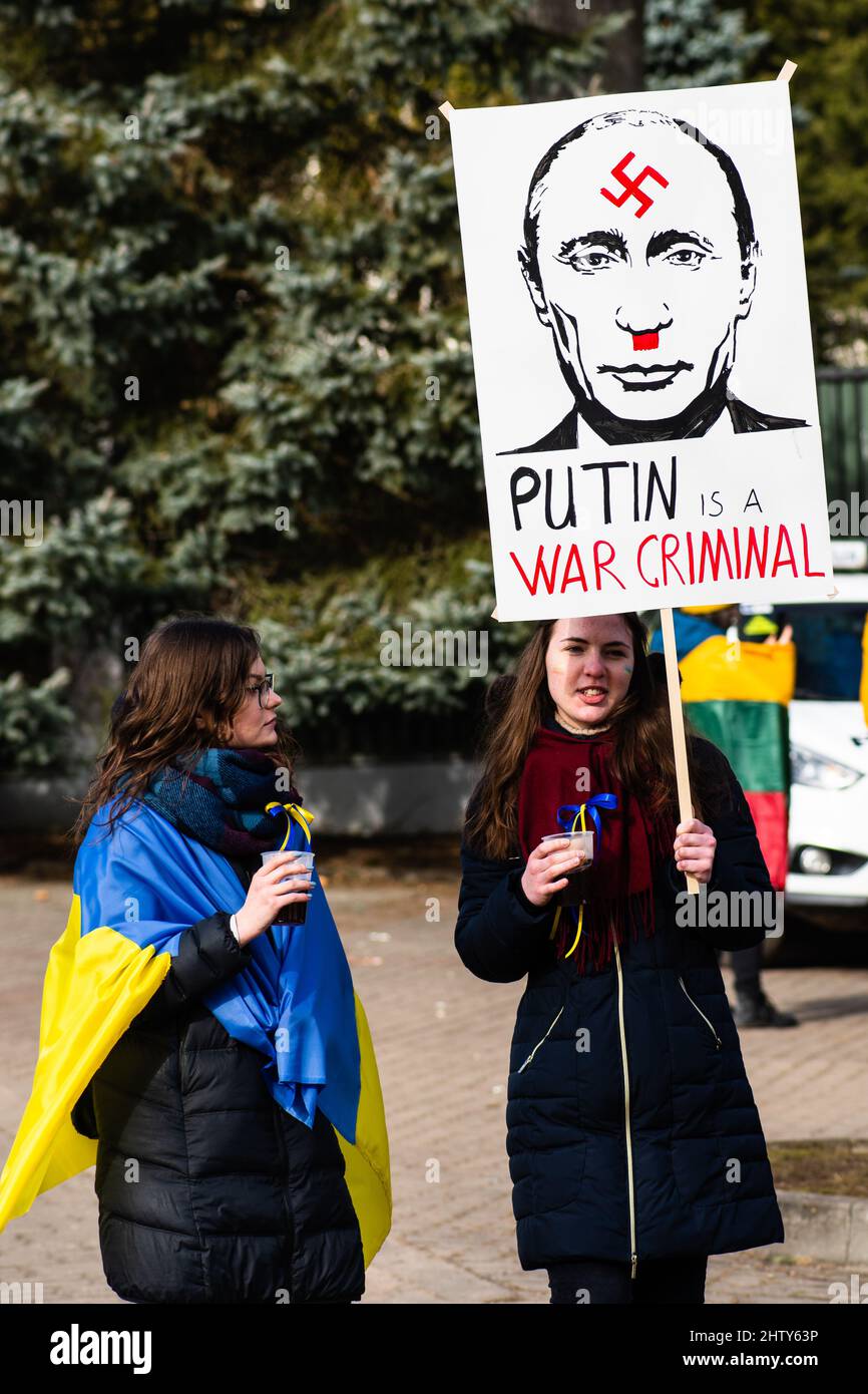 Les filles lors d'une manifestation pacifique contre la guerre, Poutine et la Russie en faveur de l'Ukraine, avec un écriteau montrant Poutine comme un criminel et des drapeaux Banque D'Images