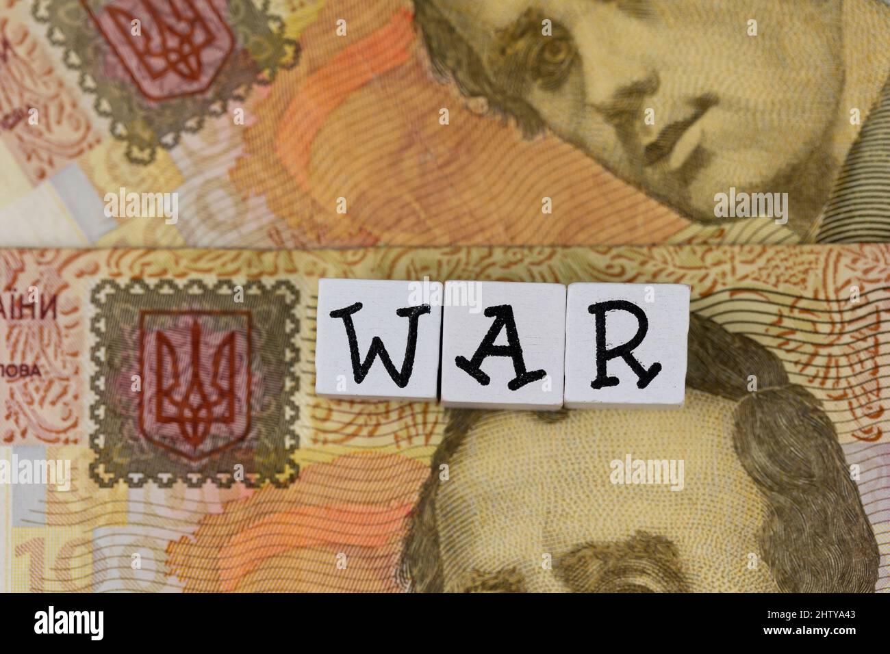 La phrase 'war' se compose de lettres sur le fond des billets ukrainiens. Photo prise sous une lumière artificielle douce Banque D'Images