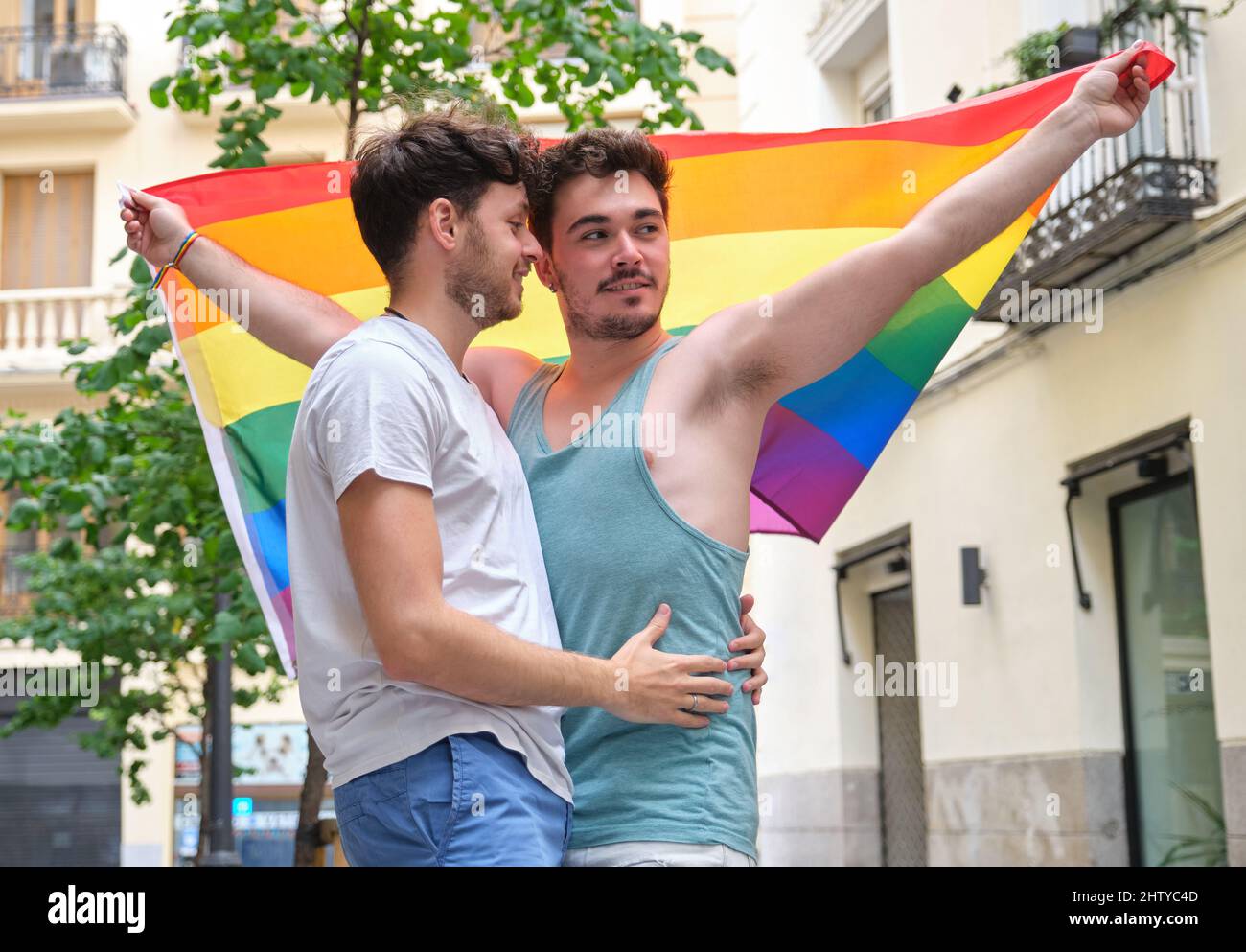 Couple gay souriant et embrassant avec un drapeau LGBT. Banque D'Images