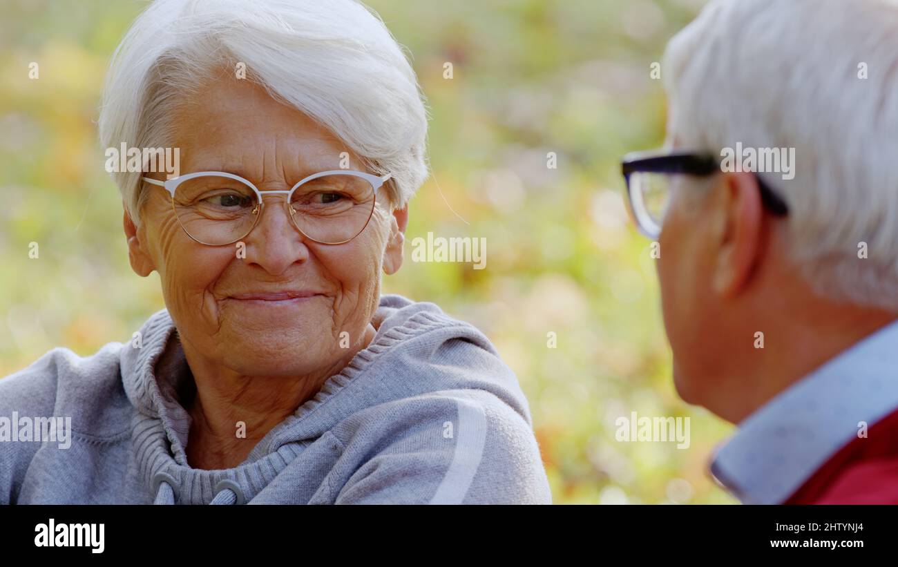 Grands-parents âgés aux cheveux gris souriant les uns les autres et parlant tout en passant du temps à l'extérieur. Photo de haute qualité Banque D'Images