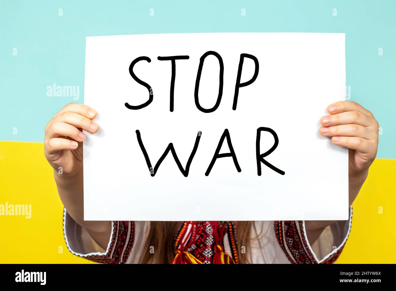 Le gros plan de l'affiche STOP WAR est tenu entre les mains d'une fille sur le fond du drapeau ukrainien. Arrêter la guerre en Ukraine. Le concept de Banque D'Images