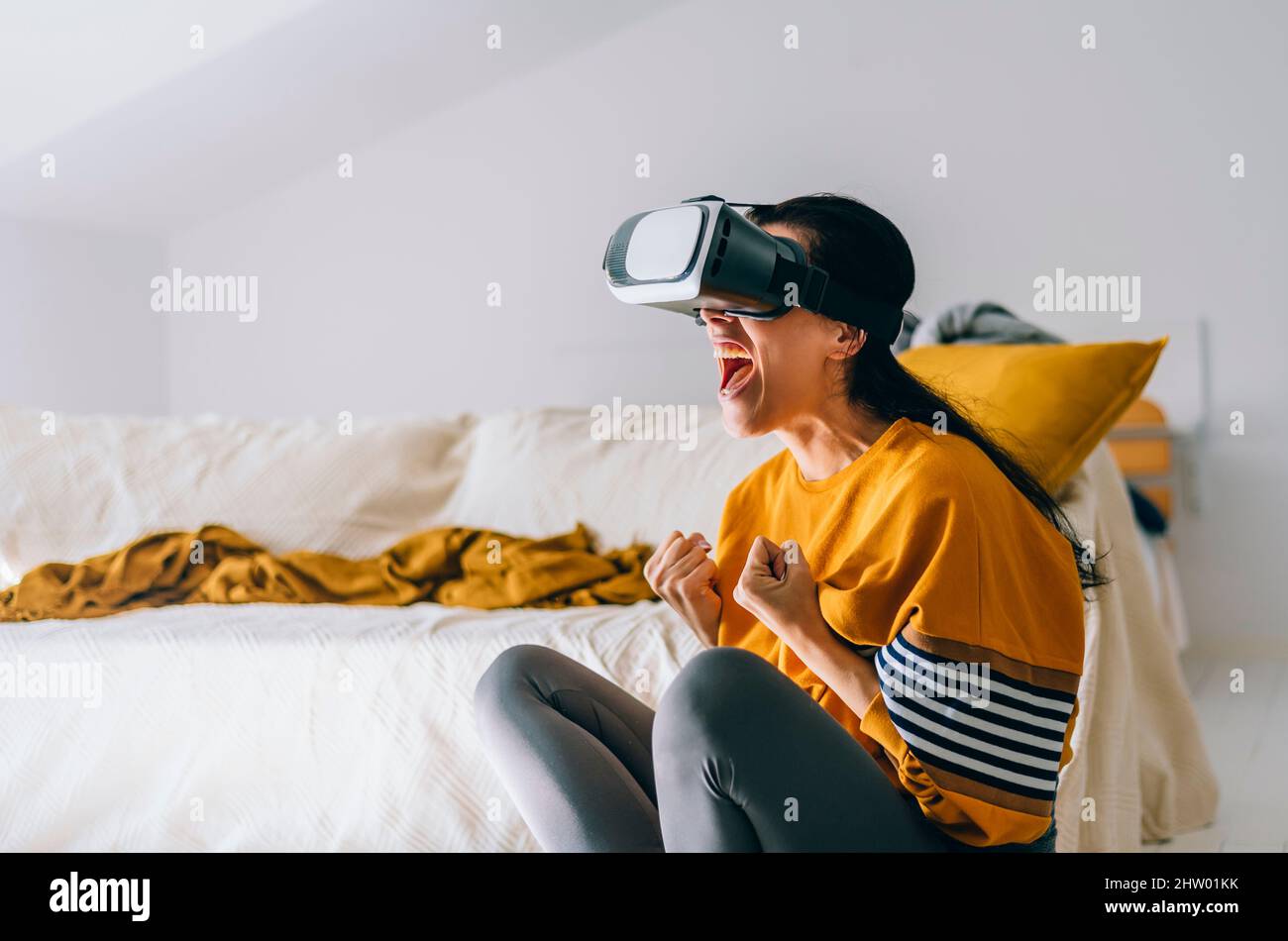 Vêtements décontractés excités femme portant des lunettes de réalité virtuelle dans le salon. Tendance future en utilisant des lunettes de réalité virtuelle pour la vidéo g Banque D'Images