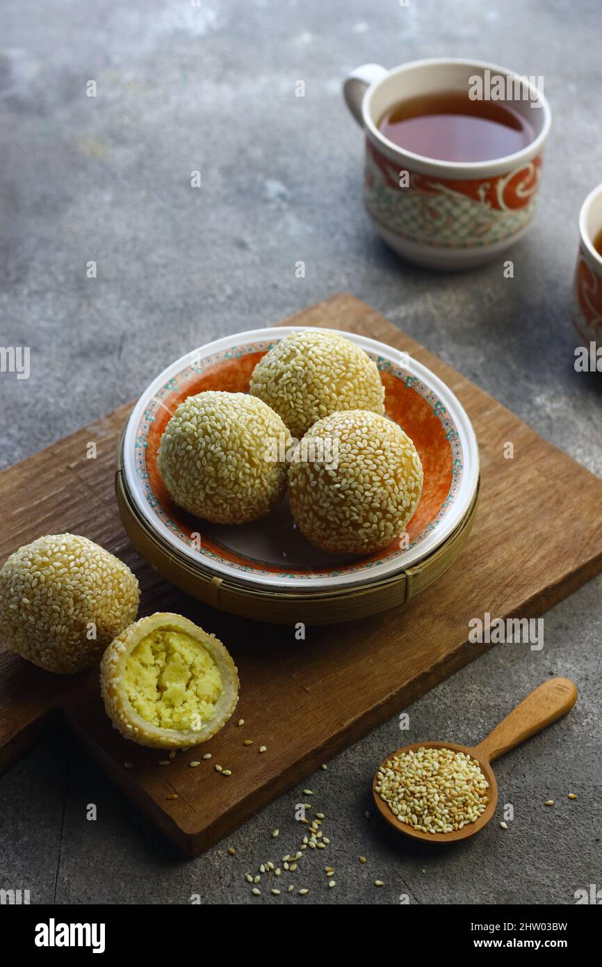 Onde de de onde ou gâteau de riz gluant boule de sésame sur plaque de céramique avec tasses de thé. Mise au point sélective, fond gris granuleux. Banque D'Images