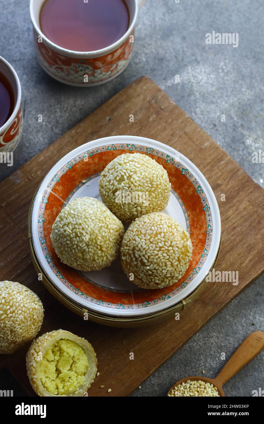 Onde de de onde ou gâteau de riz gluant boule de sésame sur plaque de céramique avec tasses de thé. Mise au point sélective, fond gris granuleux. Banque D'Images