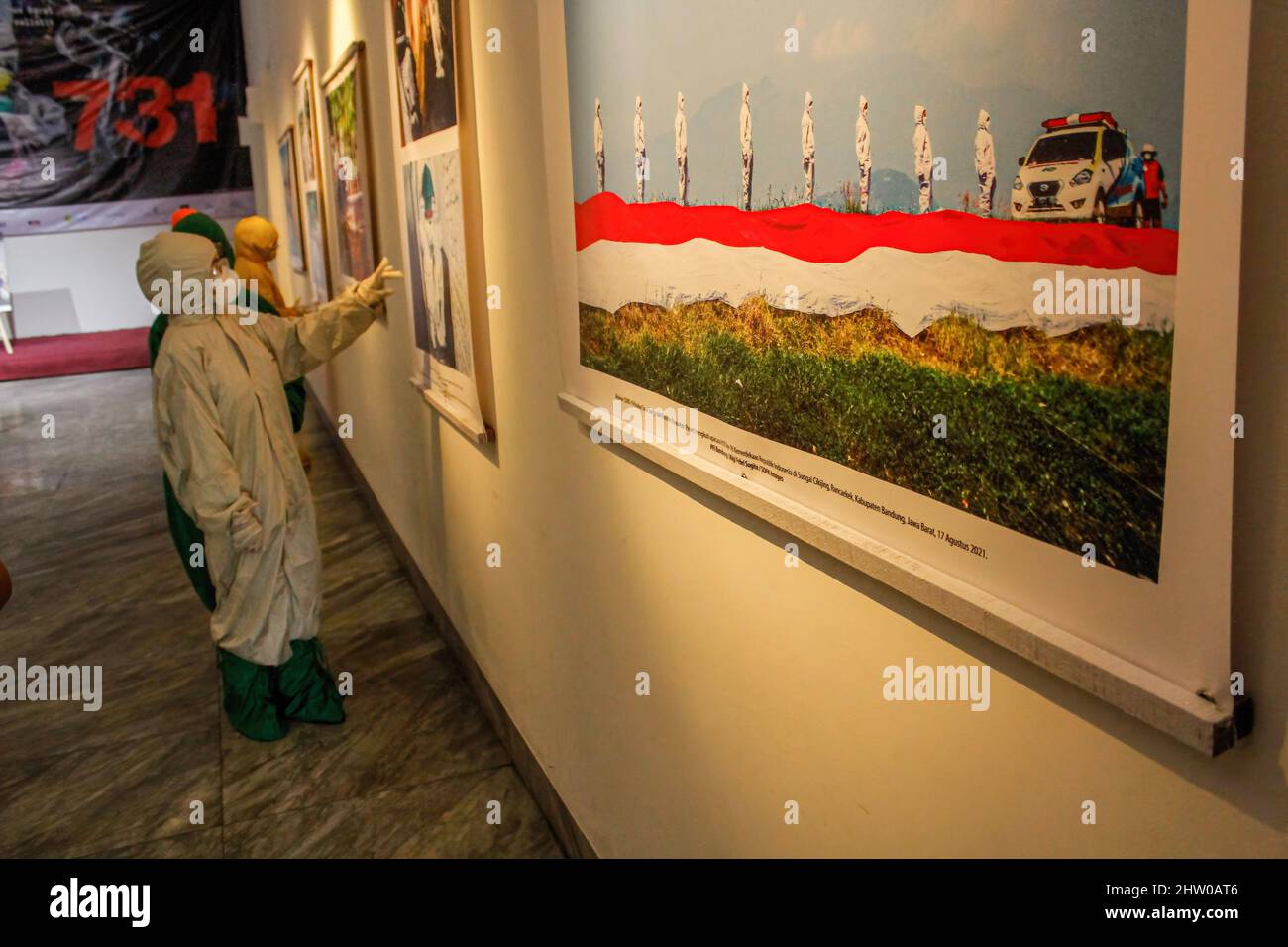 Bandung, Indonésie. 03rd mars 2022. Les visiteurs portant des combinaisons de protection contre les noisettes sont vus à l'intérieur de la Galerie lors de l'exposition pandémique de 371 jours à Bandung. Au total, 57 photos individuelles et quatre récits de photojournalistes indonésiens (PFI) Bandung ont été exposés à l'exposition de 371 jours de la pandémie en Indonésie, qui se tiendra jusqu'au 8 mars 2022. Crédit : SOPA Images Limited/Alamy Live News Banque D'Images