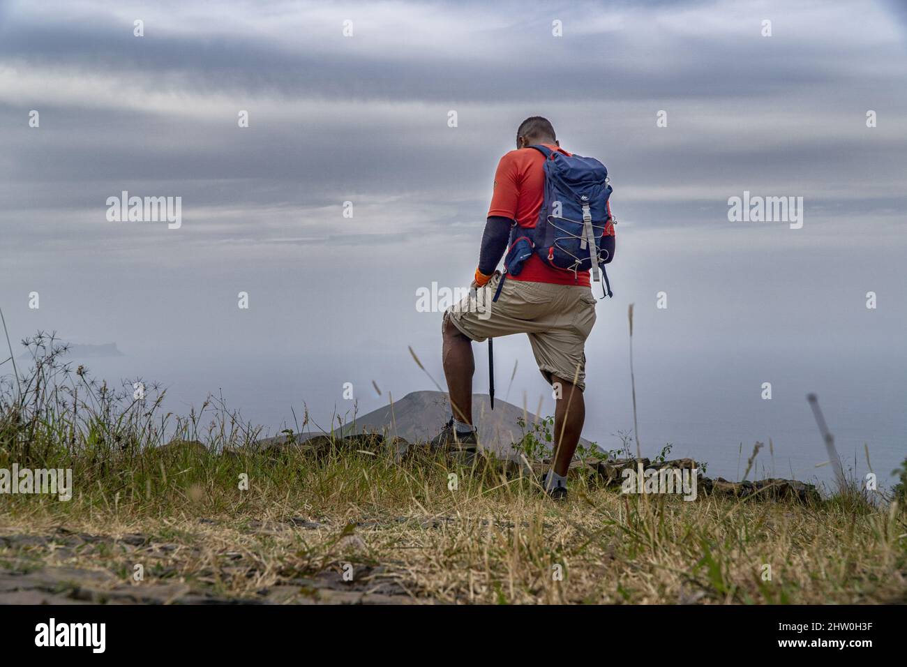 Randonneur se tenant sur le bord de la falaise et regardant vers le bas. Banque D'Images