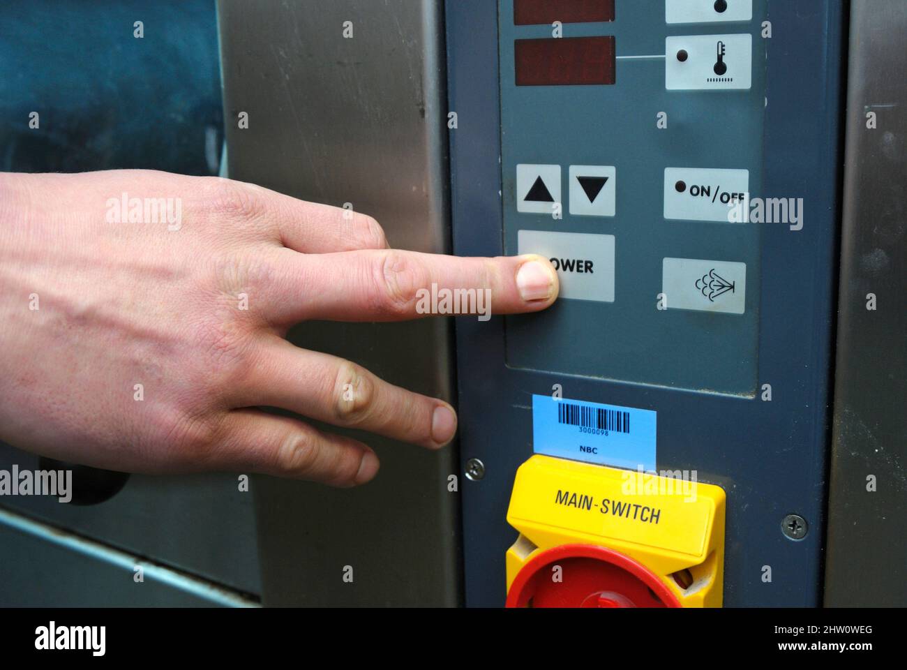 À la boulangerie: main baker appuyant sur le bouton d'alimentation d'un bandeau de commande d'un four électrique Banque D'Images