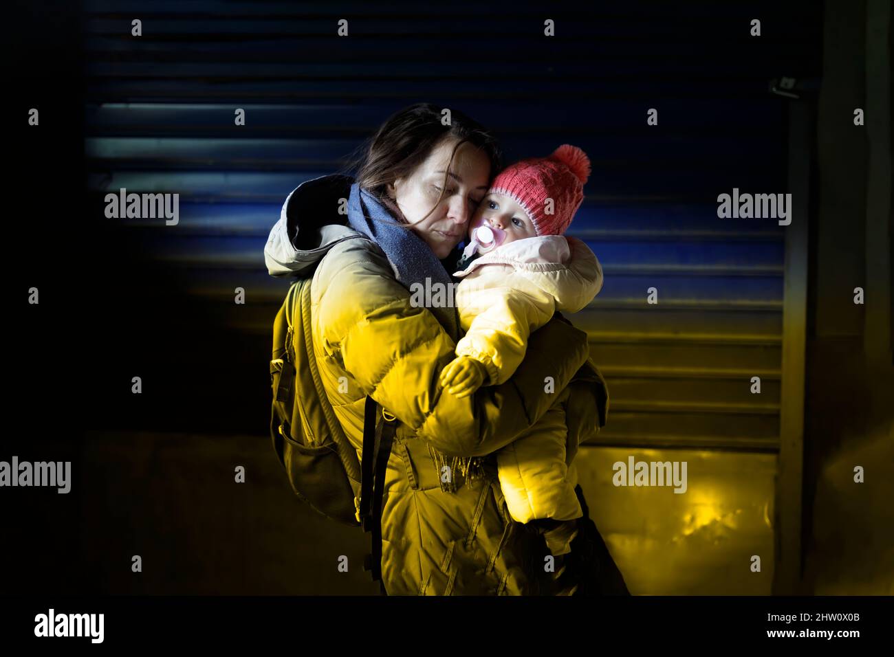 Une mère attentionnée embrasse son petit enfant dans un abri souterrain Banque D'Images