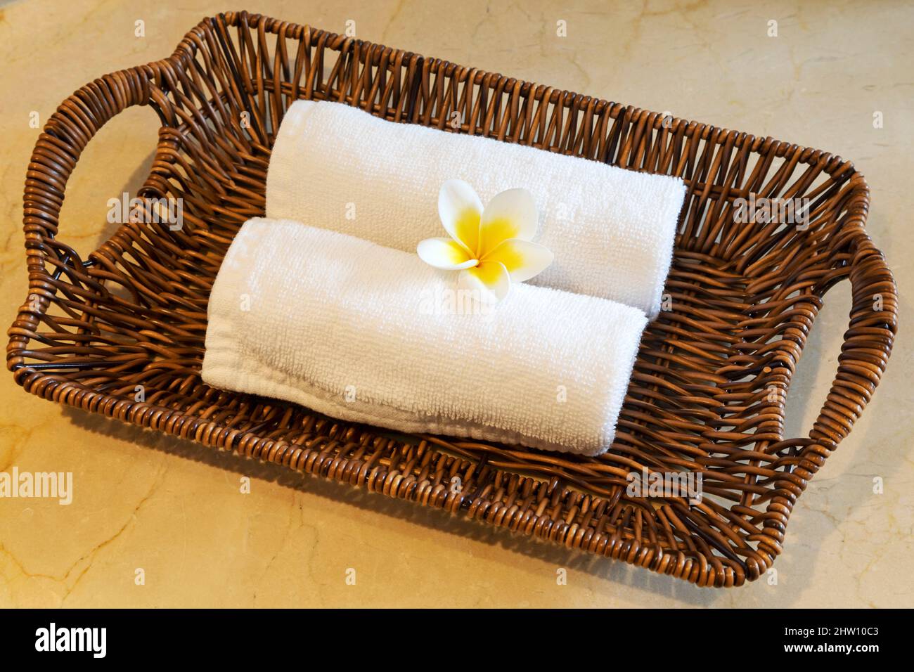 Une fleur de frangipani se compose de deux flethes disposées dans un panier en osier. Le panier est dans un hôtel de luxe. Banque D'Images