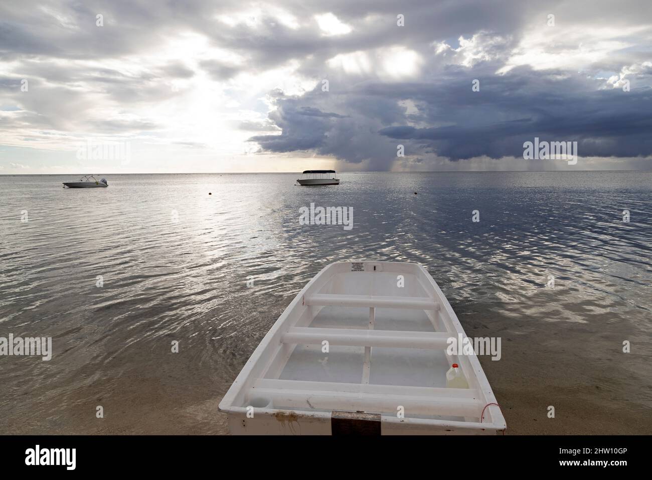 Nuages de pluie au large de la côte sud-ouest de l'île Maurice. Des bateaux flottent dans la baie de Tamarin au premier plan. Banque D'Images