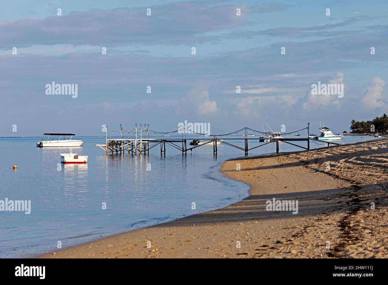 Plage lappée par l'eau de l'océan Indien à Flic an Flac à Maurice. Une jetée se jette dans l'eau de mer. Banque D'Images
