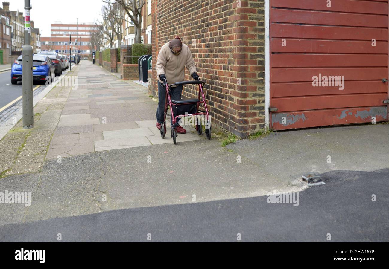 Londres, Angleterre, Royaume-Uni. Femme âgée utilisant un cadre de marche à roues à l'extérieur Banque D'Images
