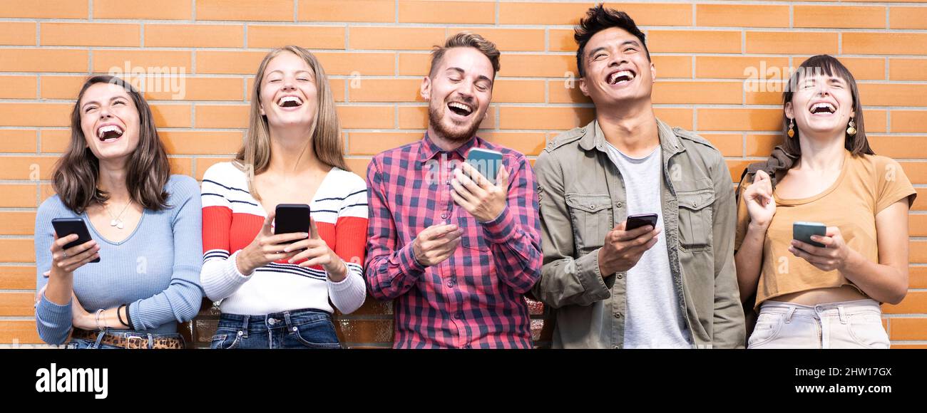 Bannière ou en-tête horizontale avec groupe d'amis heureux s'amuser avec les smartphones mobiles en plein air - les jeunes rient ensemble pendant la pause à u Banque D'Images