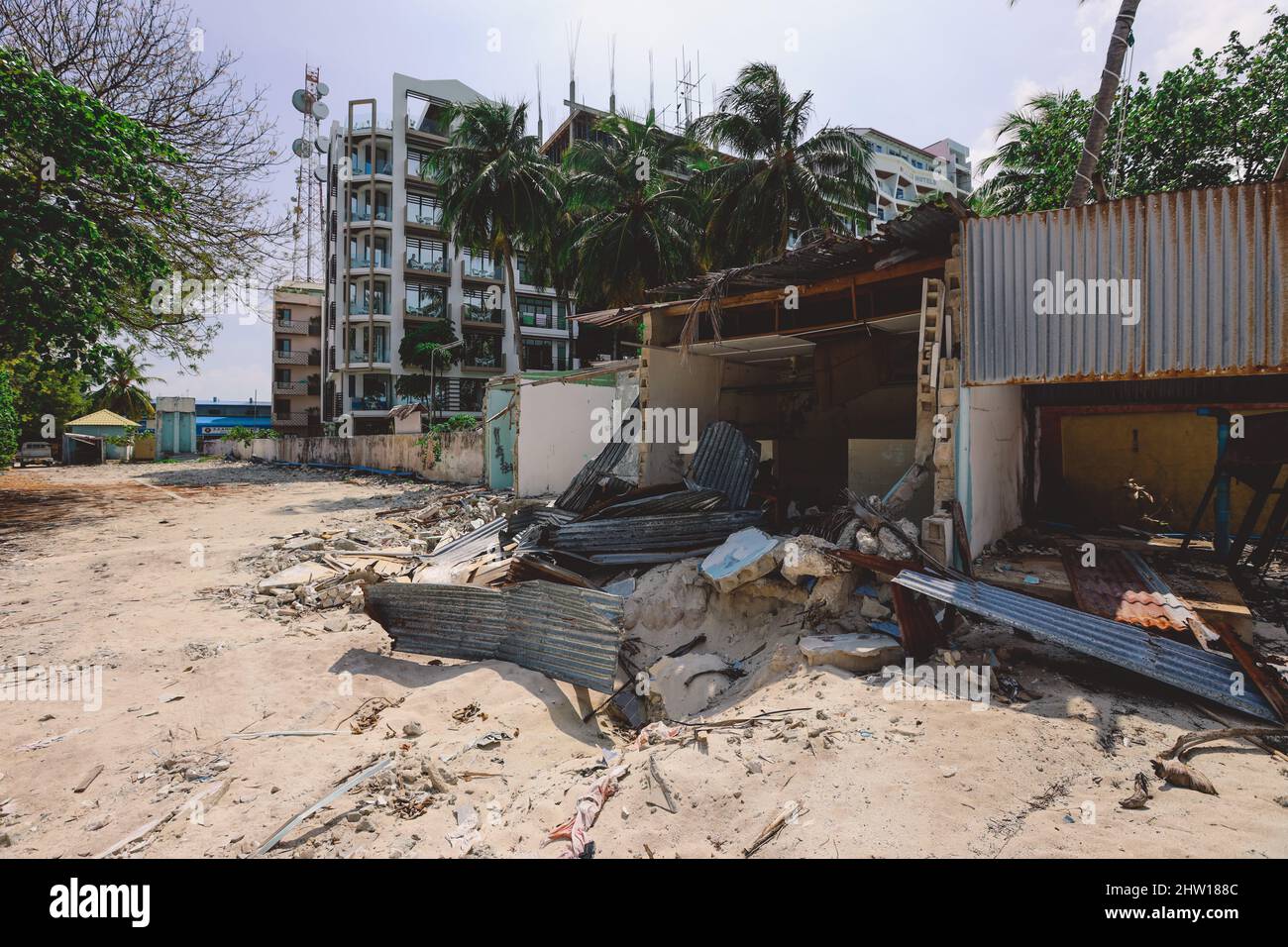 Ruines des maisons en bois avec le bâtiment de l'hôtel maldivien sur le fond, l'île de Maafushi Banque D'Images