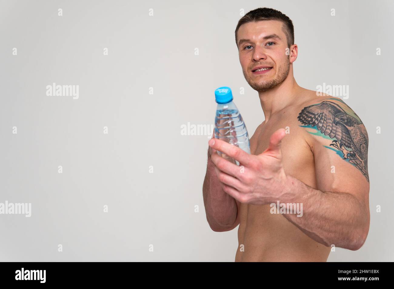 La forme physique masculine de boisson-eau est pompée avec une serviette sur un fond blanc isolé forte santé d'athlète, sport d'eau nutrition de fond hydratation jeune Banque D'Images